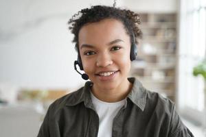 Biracial girl student in headset learning online, looking at camera. Distance education, elearning photo