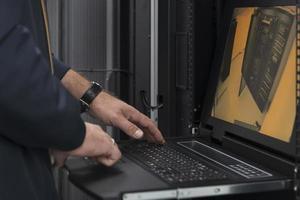 Close up on Data Center Engineer hands Using keyboard on a supercomputer Server Room Specialist Facility with Male System Administrator Working with Data Protection Network for Cyber Security. photo