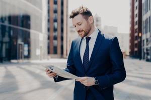 Business owner reading positive news in newspaper while walking to work photo