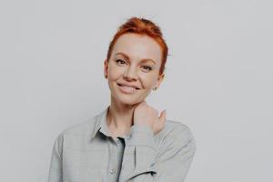 Young attractive smiling female with ginger hair in casual outfit isolated on grey studio background photo