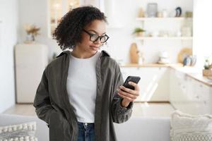 Focused young girl using smartphone at home, shopping groceries in online store with mobile apps photo