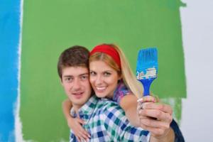 pareja feliz pintando una pared en su nuevo hogar foto