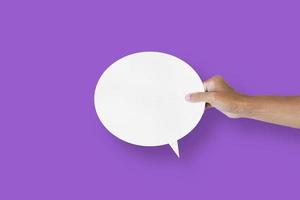 hand holding round white paper balloons speech bubbles isolated on purple background photo