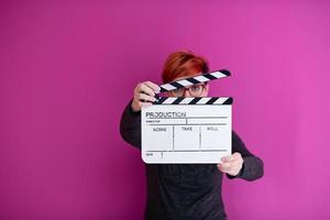 woman holding movie clapper isolated on pink background photo