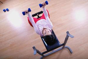 .una mujer joven levantando pesas en el gimnasio foto