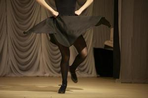 la chica baila con un vestido negro. una mujer muestra un movimiento de baile. foto