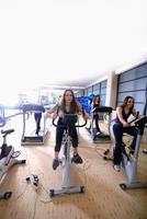 Women working out on spinning bikes at the gym photo