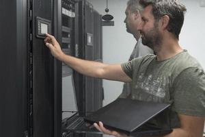 Technicians team updating hardware inspecting system performance in super computer server room or cryptocurrency mining farm. photo