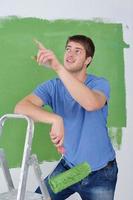 un joven apuesto pinta una pared blanca en color foto