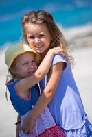 little sisters hugging on the beach coast photo