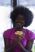 woman with afro hairstyle eating tasty pizza slice photo