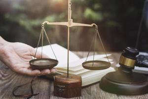 Business and lawyers discussing contract papers with brass scale on desk in office. Law, legal services, advice, justice and law concept picture with film grain effect photo