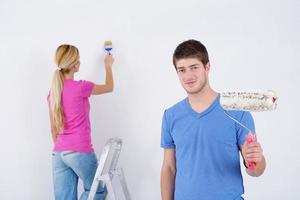 happy couple paint wall at new home photo