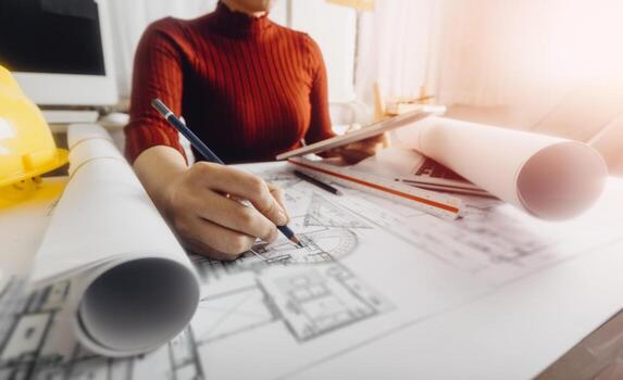 Two colleagues discussing data working and tablet, laptop with on on architectural project at construction site at desk in office photo