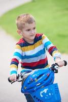 niño feliz aprendiendo a andar en bicicleta foto