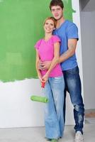 pareja feliz pintando una pared en su nuevo hogar foto