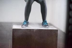 black woman is performing box jumps at gym photo