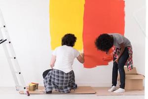 Pareja multiétnica pintando paredes interiores foto