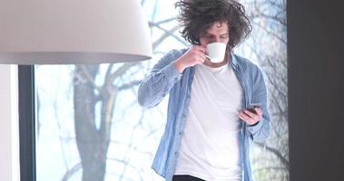 young man drinking coffee and using a mobile phone  at home photo