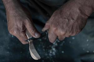 Hands carving spoon from wood, working with chisel close up. Wooden workshop. Process of making wooden spoon photo