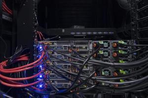 primer plano de la sala del servidor de red en el concentrador o conmutador de fibra óptica para comunicaciones digitales e Internet en la supercomputadora del centro de datos de negocios corporativos de mainframe. foto