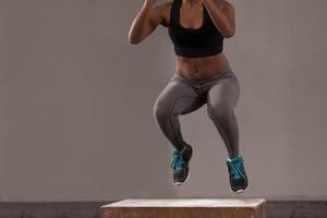 black woman is performing box jumps at gym photo