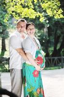 Happy pregnant couple at beautiful sunny day in park photo
