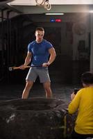 man workout with hammer and tractor tire photo