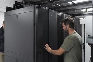 Technicians team updating hardware inspecting system performance in super computer server room or cryptocurrency mining farm. photo