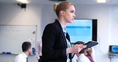 mujer de negocios usando tableta con compañeros de trabajo en backgorund teniendo reunión foto