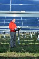 engineer using laptop at solar panels plant field photo