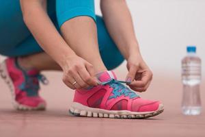 Young woman tying shoelaces on sneakers photo