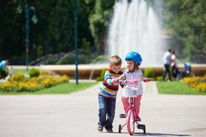 niño y niña en el parque aprendiendo a andar en bicicleta foto