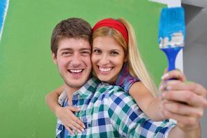 pareja feliz pintando una pared en su nuevo hogar foto