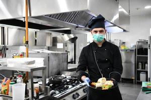 chef cook wearing face protective medical mask for protection from coronavirus photo