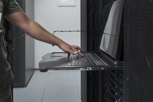 cierre las manos del ingeniero del centro de datos usando el teclado en una instalación especializada en la sala de servidores de supercomputadoras con un administrador de sistemas masculino que trabaja con la red de protección de datos para la seguridad cibernética. foto