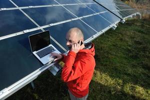 ingeniero que usa una computadora portátil en el campo de la planta de paneles solares foto