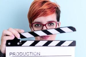 woman holding movie clapper against cyan background photo