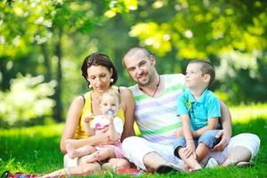 Feliz pareja joven con sus hijos divertirse en el parque foto