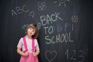 school girl child with backpack writing  chalkboard photo