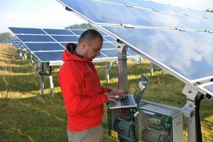 engineer using laptop at solar panels plant field photo