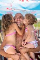 portrait of young happy father with daughters by the sea photo