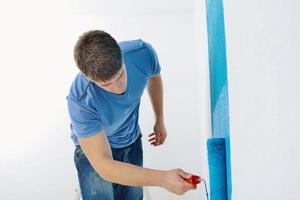 handsome young man paint white wall in color photo