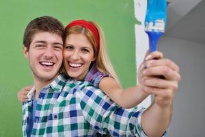 pareja feliz pintando una pared en su nuevo hogar foto