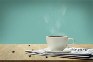 White cup of Espresso with Newspaper on the wooden table photo