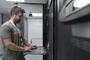 Data Center Engineer Usaing Keyboard on a Supercomputer Server Room Specialist Facility with Male System Administrator photo