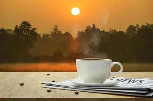 taza de café con periódico sobre la mesa de madera y el fondo del pantano foto