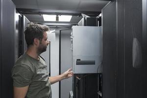 IT engineer working In the server room or data center The technician puts in a rack a new server of corporate business mainframe supercomputer or cryptocurrency mining farm. photo