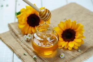 Honey jar with dipper and flowing honey, canvas background photo