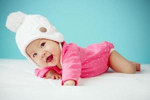 Little baby in knit winter clothing closing face with knitted beanie photo